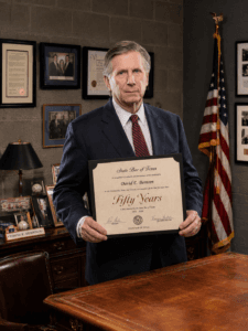 David E. Bernsen proudly displaying his State Bar of Texas Fifty-Year Lawyer certificate in his office.